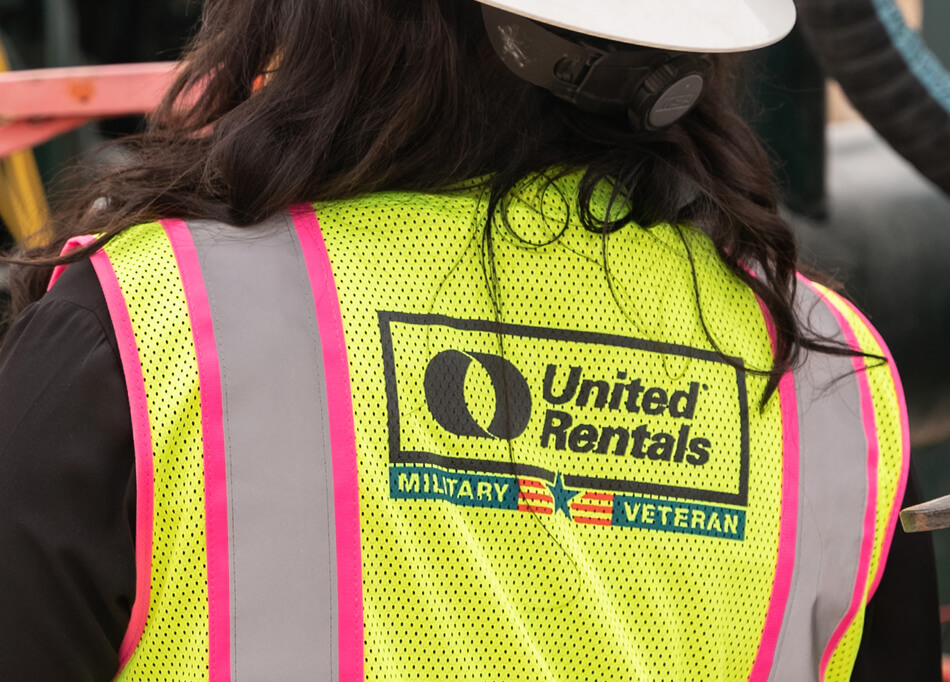 Le dos d'une employée de United Rentals vêtue d'un gilet jaune portant la désignation d'ancien combattant.